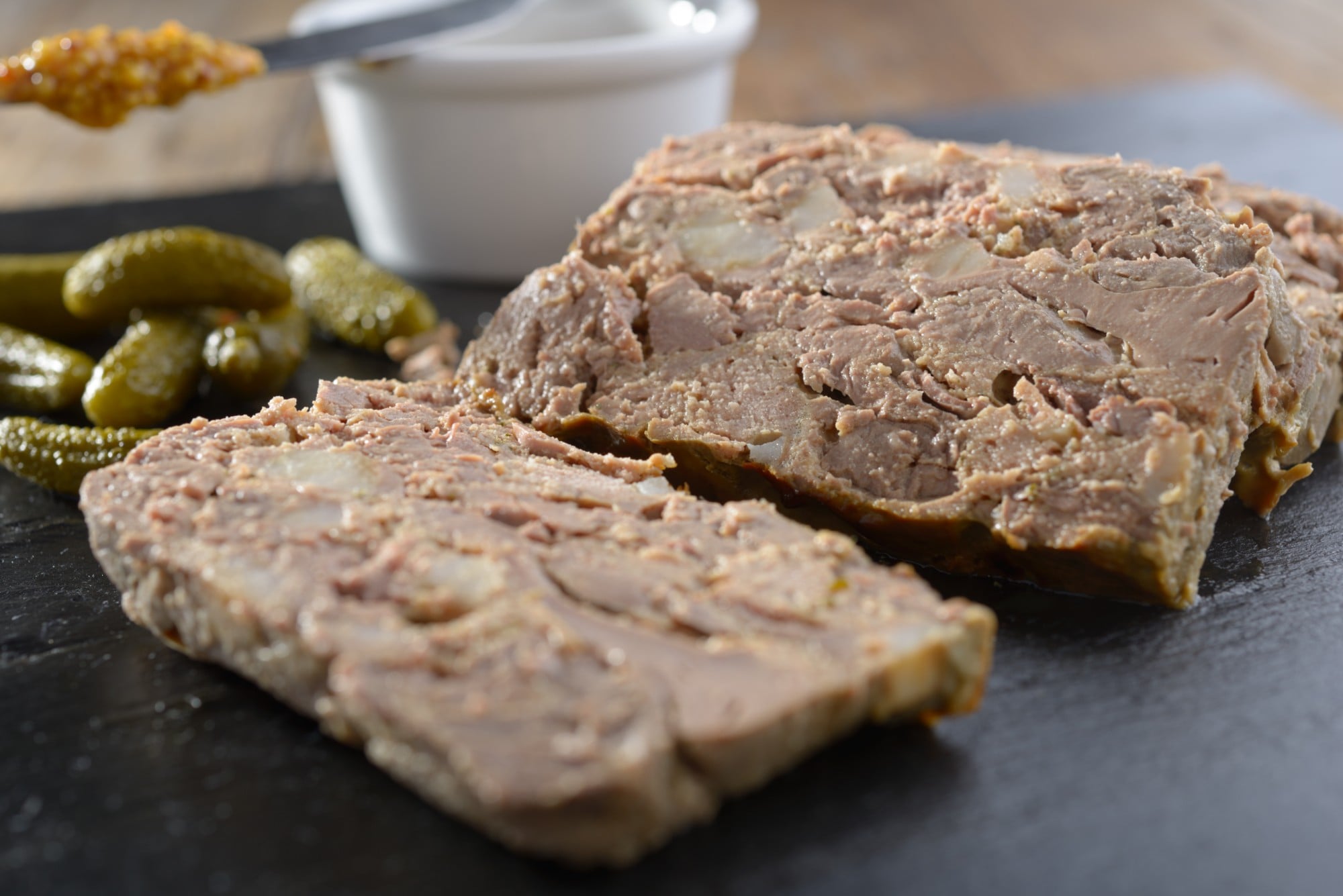 Pâté de gibier tranché avec cornichons et moutarde sur une planche en ardoise
